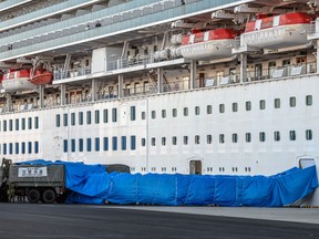 Members of Japans self-defence forces place tarpaulin over a walkway to a military truck from the Diamond Princess cruise ship at Daikoku Pier where it is being resupplied and newly diagnosed coronavirus cases taken for treatment as it remains in quarantine after a number of the 3,700 people on board were diagnosed with coronavirus, on February 10, 2020 in Yokohama, Japan.