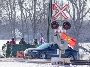 Protesters stand on the closed train tracks on the ninth day of the blockade in Tyendinaga Mohawk Territory, near Belleville, Ont., Friday, Feb. 14, 2020. Alberta Premier Jason Kenney says the ongoing protest blockades shutting down rail service across Canada are fast becoming a full-blown economic crisis.
