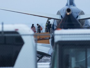 Passengers step off a plane carrying Canadians back from the Wuhan province in China, after it arrived at Canadian Forces Base Trenton in Trenton, Ont., on Tuesday, Feb. 11, 2020.