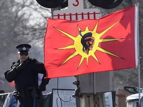 An Ontario Provincial Police officer talks on a radio after arrests were made at a rail blockade in Tyendinaga Mohawk Territory, near Belleville, Ont., on Feb. 24, 2020.