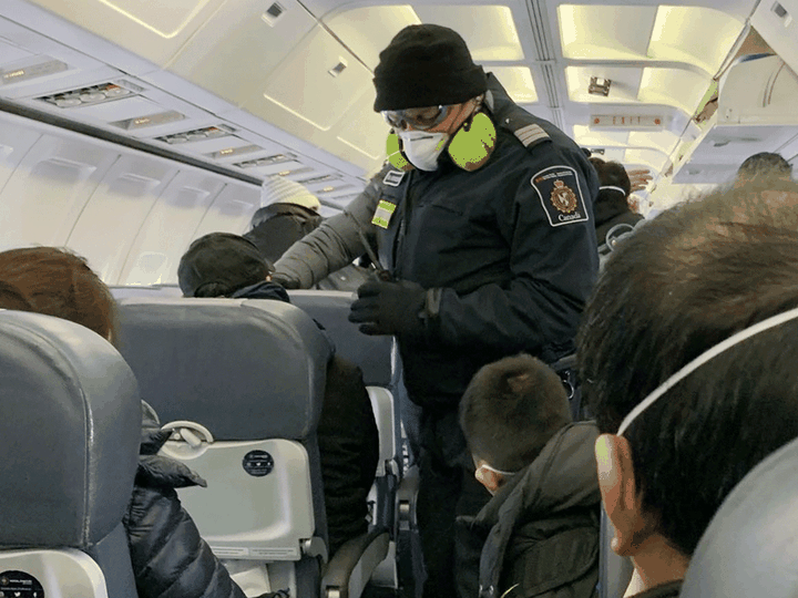  An RCMP officer checks Canadians one their way to quarantine at CFB Trenton, after being evacuated from China due to the coronavirus outbreak, Feb. 7, 2020. Courtesy of Edward Wang via Reuters