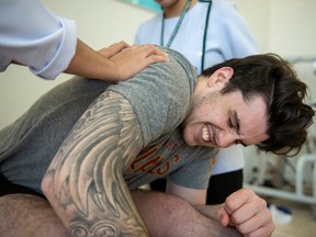 Ryan Straschnitzki winces during a stretching exercise at a physiotherarpy session at World Medical Hospital in Nonthaburi, Thailand on Friday, December 6, 2019.