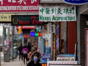 A woman, wearing a mask, walks in the Chinatown district of downtown Toronto, Ontario, after so far, three patients with novel coronavirus were reported in Canada January 28, 2020.
