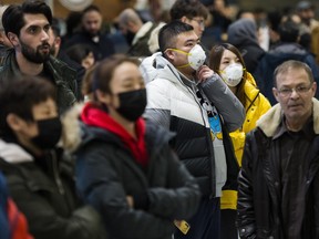 People wear masks as they wait for the arrivals at the International terminal at Toronto Pearson International Airport in Toronto on Jan. 25, 2020.