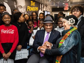 June Girvan, president of Black History Ottawa, shakes hands with Willie O'Ree, the first black player in the NHL and a member of the Hockey Hall of Fame, as he sits for a photo with students from St. Peter's High School in the Black Hockey History Mobile Museum in Ottawa on Feb. 3, 2020.