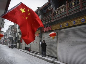 Chinese mans wears a protective mask as he waits in an empty and shuttered commercial street on February 5, 2020 in Beijing, China.