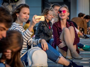 Young people sit on a bridge over the Moskva River in downtown Moscow on Sept. 11, 2017.