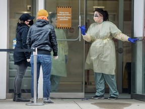 A nurse speaks to people asking for a COVID-19 test at St. Michael's Hospital in Toronto during the ongoing COVID-19 pandemic, March 30, 2020.