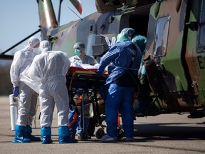Medical staff load a patient infected with the Covid-19 virus into a French military helicopter heading to Switzerland to ease the situation in eastern France, Monday, March 30 2020 in Strasbourg, eastern France.