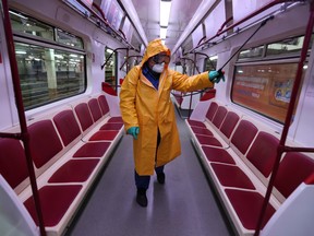 An employee wearing protective gear sprays disinfectant to sanitize a tube train over coronavirus fears in Tbilisi, Georgia March 2, 2020.