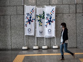 A woman walks past Tokyo 2020 Olympics banners on March 19, 2020 in Tokyo, Japan. As Japanese and IOC officials continued to insist that the Games would go ahead as planned, Japans Deputy Prime Minister said on Wednesday that the Tokyo Olympics are cursed, as speculation grows that the Olympics will have to be postponed due to the ongoing coronavirus (COVID-19) pandemic.