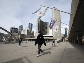A small group of pedestrians pass through Nathan Phillips Square in front of Toronto City Hall as Torontonians adjust to the new normal.