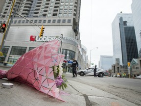 Flowers seen on Yonge Street as police officers work in the background, in the wake of the van attack in Toronto.