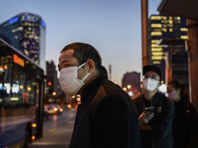 Chinese commuters wear protective masks as they line up in a staggered formation while waiting for a bus at the end of the work day on March 20, 2020 in Beijing, China.