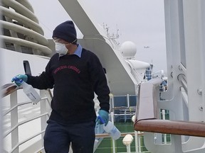 A cruise ship worker cleans a railing on the Grand Princess Thursday, March 5, 2020, off the California coast.