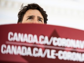 Prime Minister Justin Trudeau speaks from behind a podium bearing the link to a federal government website about the coronavirus disease during a press conference about COVID-19 in front of his residence at Rideau Cottage in Ottawa, on Sunday, March 22, 2020.