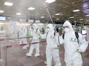 South Korean soldiers wearing protective gear spray disinfectant to help prevent the spread of the COVID-19, at the Daegu International Airport in Daegu on March 6, 2020.