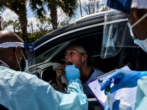 A medical personnel member takes samples of Lee Dinzik at a "drive-thru" coronavirus testing lab set up by a local community centre in West Palm Beach, north of Miami, on March 16, 2020.