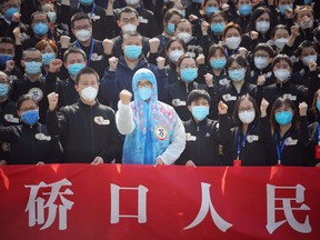 Members of a medical assistance team from Jiangsu province chant slogans at a ceremony marking their departure after helping with the COVID-19 coronavirus recovery effort, in Wuhan, in China's central Hubei province on March 19, 2020.