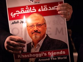 In this file photo taken on October 25, 2018 shows a demonstrator holding a poster picturing Saudi journalist Jamal Khashoggi and a lightened candle during a gathering outside the Saudi Arabia consulate in Istanbul.