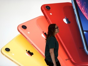 An Apple Store employee walks past an illustration of iPhones at the new Apple Carnegie Library during the grand opening and media preview in Washington, U.S., May 9, 2019.