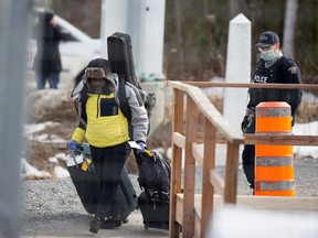 An asylum seeker crosses the border from New York into Canada followed by an RCMP officer at Roxham Road in Hemmingford, Quebec, March 18, 2020.