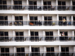 Passengers look out from the cabins of their cruise ship as it sits moored in Sydney Harbour a day before its expected departure on March 17, 2020.