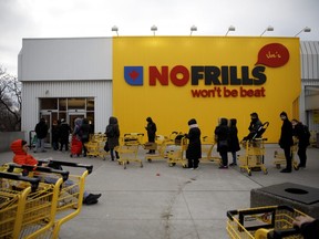 Shoppers wait in line to enter a No Frills supermarket in Toronto, Ontario, March 14, 2020.