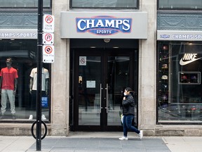 A pedestrian walks past a Champs Sports store on Yonge Street in Toronto that has been shuttered as a result of the COVID-19 pandemic, on March 19, 2020.
