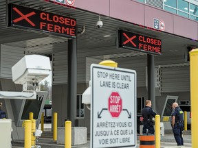 Canadian Border Services Agency officers stand in front of two closed border checkpoints at the Thousand Islands Bridge in Lansdowne, Ont., on March 19, 2020.