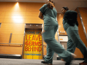 Staff walk past a sign indicating to wash hands on the elevator doors at the Jewish General Hospital in Montreal.