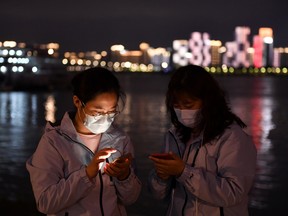 Medical workers from outside Wuhan check their mobile phones at a riverside park by the Yangtze River in Wuhan of Hubei province, the epicentre of China's coronavirus disease (COVID-19) outbreak, March 26, 2020.