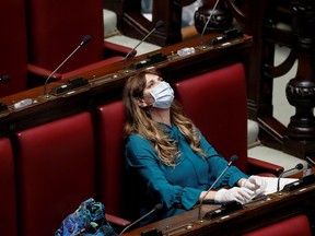 Deputy Maria Teresa Baldini of Fratelli d'Italia party wears a protective mask and gloves inside the low house parliament building after Italy orders a lockdown on the whole country aimed at beating the coronavirus, in Rome, Italy, March 11, 2020.