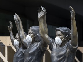 Surgical masks placed on a statue in front of Princess Margaret Hospital in downtown Toronto on March 19, 2020.