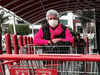 A woman wearing a face mask as a preventive measure against the spread of COVID-19, pushes a shopping cart.