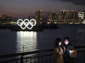 Two women take a selfie with the Olympic rings in the background in the Odaiba section of Tokyo, Thursday, March 12, 2020.