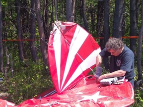 A Transportation Safety Board investigator examines the wreckage of a Pitts S2E aircraft following an accident in Saint-Jean-Port-Joli, Que., in this 2019 handout photo. The Transportation Safety Board says an amateur-built aircraft that crashed northeast of Quebec City in June 2019 with two aboard was doing aerobatic maneuvers on the day of the crash. The agency released its report today into the accident involving a Pitts S2E aircraft that crashed shortly after takeoff at the Saint-Jean-Port-Joli Aerodrome on June 16.
