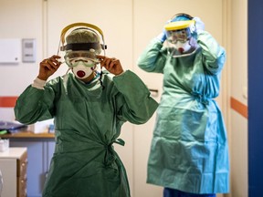 Nurses put on protective gear in a ward designated for new patents infected with the coronavirus in a hospital in Budapest, Hungary, Monday, March 16, 2020. Veterans from the frontlines of infectious disease see three potential challenges looming in the care of Canada's sickest COVID-19 patients: intensive care space, surplus ventilators and keeping specialized staff healthy.
