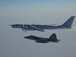 An American F-22 escorts a Russian Tu-142 Bear aircraft in international airspace near Alaska in this March 2020 handout photo. Military authorities say U.S. and Canadian fighter jets were scrambled Monday to intercept two Russian reconnaissance planes travelling near the North American coastline. The North American Aerospace Defence Command says the two Russian Tu-142 Bear aircraft flew within 92 kilometres remained in international airspace north of Alaska for about four hours before departing.