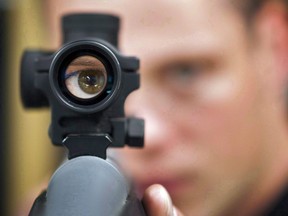 In this Sept. 15, 2010 file photo, an employee looks through the scope of long gun at a gun store in Calgary, Alta. The COVID-19 outbreak coupled with fears about more restrictive gun legislation has fuelled a spike in firearm and ammunition sales, several dealers said this week.THE CANADIAN PRESS/Jeff McIntosh