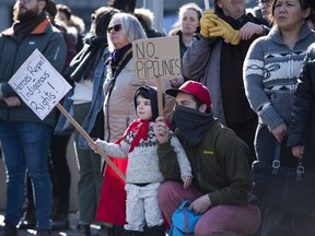 People stand on Wellington Street in Ottawa during a rally in solidarity with Wet'suwet'en hereditary chiefs opposed to the Costal GasLink Pipeline, on Monday, Feb. 24, 2020. A new poll suggests Canadians weren't happy with Justin Trudeau's handling of the natural-gas pipeline dispute in British Columbia that led to nationwide rail and road blockades mounted in solidarity with Indigenous leaders who oppose the project.