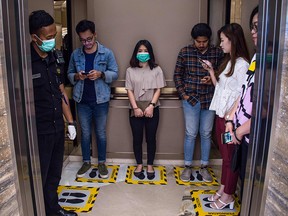 People stand on designated areas to ensure social distancing inside an elevator at a shopping mall in Surabaya, Indonesia, on March 19, 2020, amid concerns of the COVID-19 coronavirus outbreak.