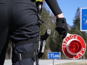 German police guards secure the access road from Germany to enter Austria after the border is sealed to foreigners at a border crossing point near Garmisch-Partenkirchen on March 16.