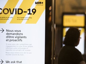 A woman walks by a COVID-19 information sign at Central Station in Montreal, Wednesday, March 18, 2020, as COVID-19 cases rise in Canada and around the world.