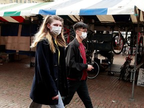 People wearing face masks walk through a market in Cambridge as the number of coronavirus cases grow around the world, in Cambridge, Britain, March 17, 2020.