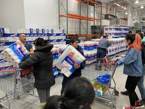 Workers ration toilet paper to one package per Costco member in an effort to stem hoarding due to fears over the coronavirus, at a Costco store in Toronto on March 14.