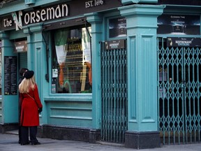 Two people read the closure notice in the window of The Norseman pub, as bars across Ireland close voluntarily to curb the spread of coronavirus, in Dublin, Ireland, March 15, 2020.