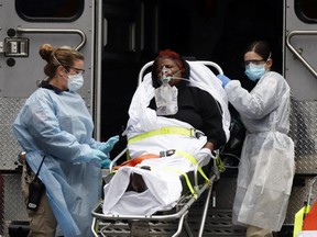 Emergency Medical Technicians (EMT) wearing protective gears wheel a sick patient to a waiting ambulance during the outbreak of coronavirus disease (COVID-19) in New York City, New York, U.S., March 28, 2020.