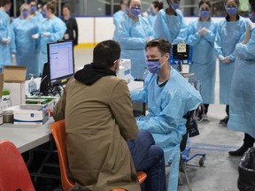 A health care worker speaks to a test patient, a staff member portraying the role of a patient to ensure the assessment systems are working, at an assessment table, as they prepare for the opening of the COVID-19 Assessment Centre at Brewer Park Arena in Ottawa on March 13.