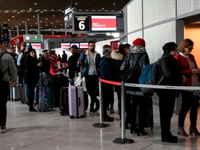 Travellers queue at an airport information desk at Paris-Charles-de-Gaulle airport after a US 30-day ban on travel from Europe due to the COVID-19 spread in Roissy-en-France on March 12, 2019.